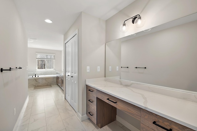 full bath featuring vanity, baseboards, a garden tub, and marble finish floor