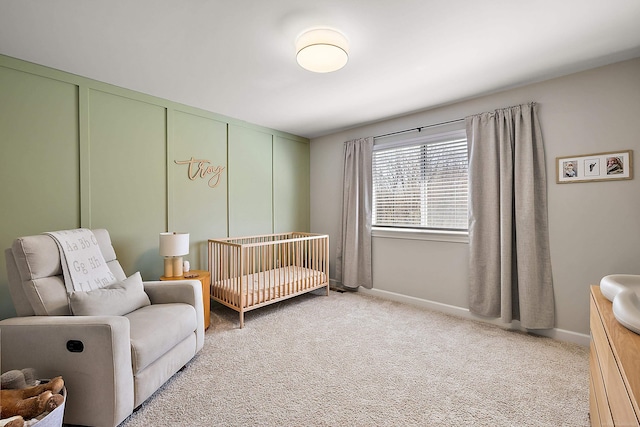 bedroom featuring a nursery area, baseboards, and light colored carpet
