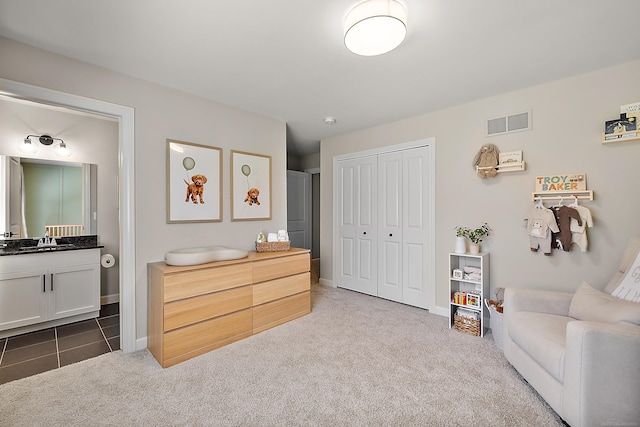 bedroom featuring visible vents, a sink, baseboards, a closet, and carpet flooring