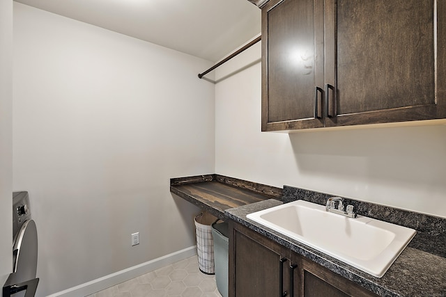 laundry area with washer / clothes dryer, cabinet space, a sink, baseboards, and light tile patterned floors