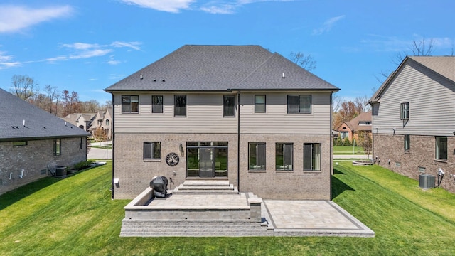 back of property with a yard, brick siding, central AC unit, and a patio area