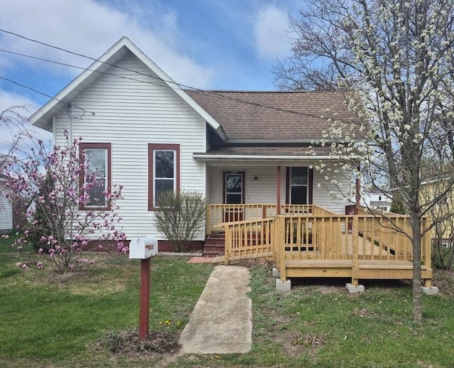 bungalow-style house featuring a porch, a front lawn, and roof with shingles
