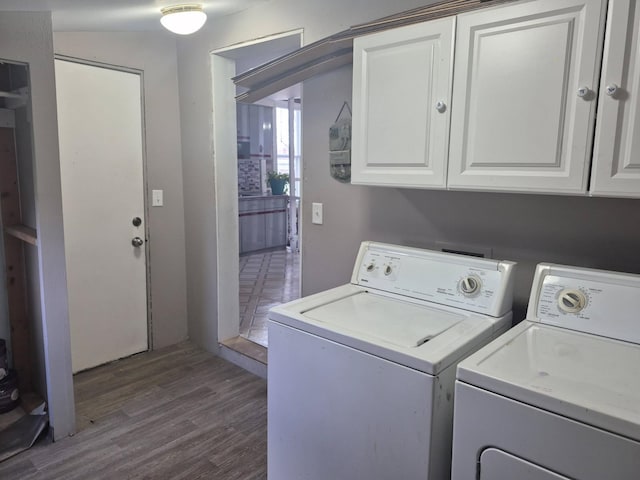 laundry room featuring dark wood-type flooring, washer and clothes dryer, and cabinet space