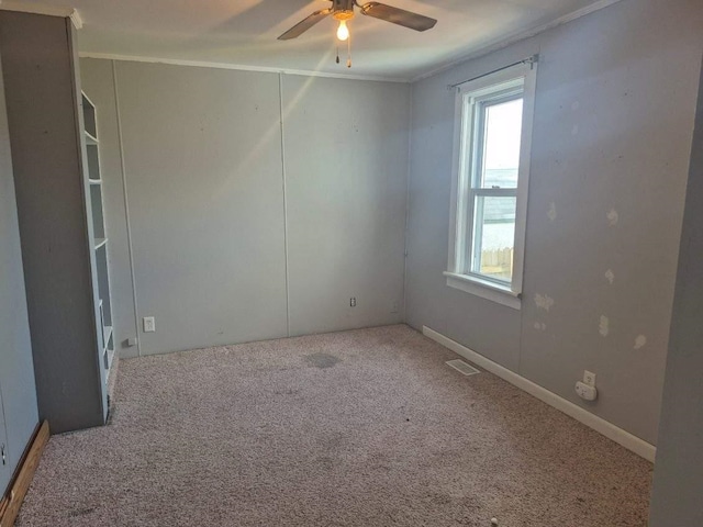 unfurnished room with carpet flooring, ceiling fan, visible vents, and crown molding