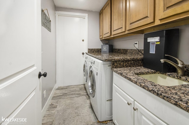 washroom with cabinet space, separate washer and dryer, baseboards, and a sink