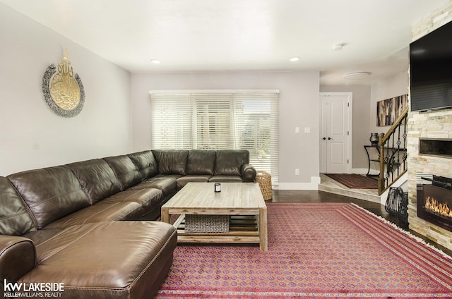 living room featuring a stone fireplace, recessed lighting, baseboards, and wood finished floors