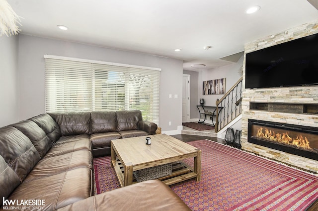 living room featuring recessed lighting, baseboards, stairs, and a stone fireplace