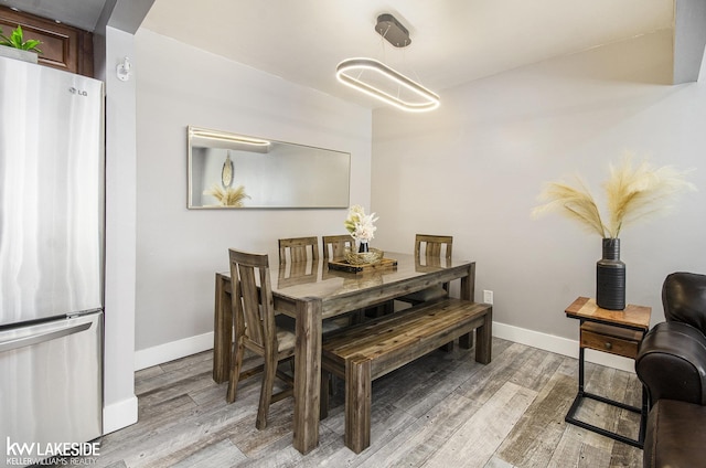 dining space with arched walkways, baseboards, and light wood-style flooring