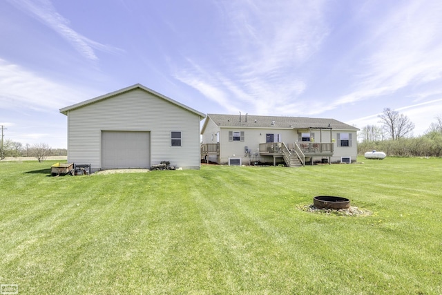 8765 Winn Rd, Brown City, MI 48416 - rear view of property featuring a lawn, a deck, a garage, an outdoor structure, and a fire pit