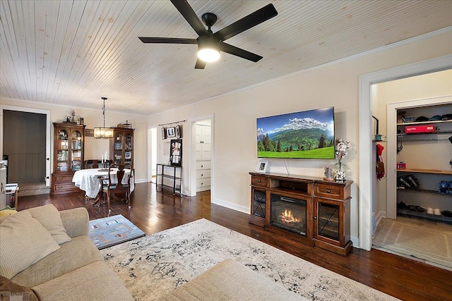 living area featuring ceiling fan, crown molding, baseboards, wood-type flooring, and a glass covered fireplace