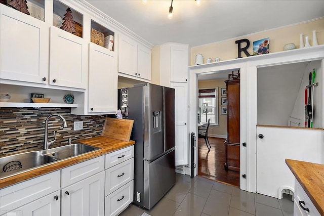 kitchen with stainless steel refrigerator with ice dispenser, open shelves, wood counters, and dark tile patterned floors