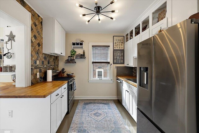 kitchen with dark tile patterned flooring, tasteful backsplash, stainless steel appliances, and a chandelier