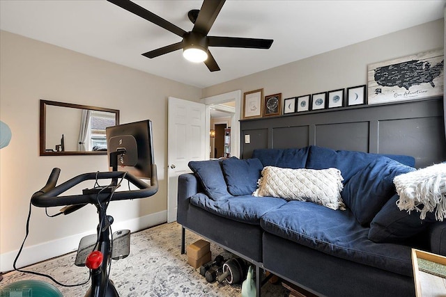 living area with baseboards and a ceiling fan