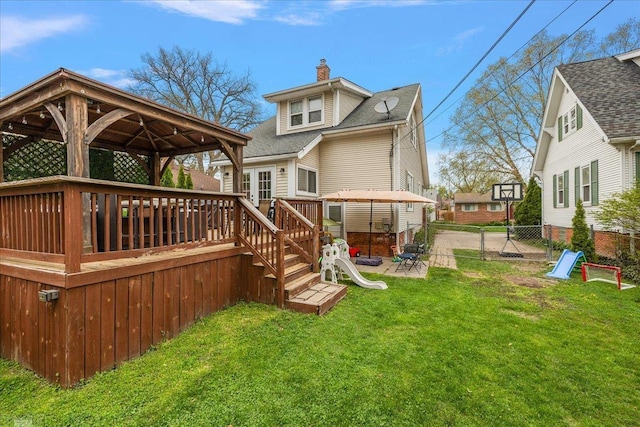 rear view of house with a lawn, a deck, a fenced backyard, a chimney, and a gazebo