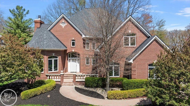 view of front of home featuring a shingled roof, a chimney, and brick siding
