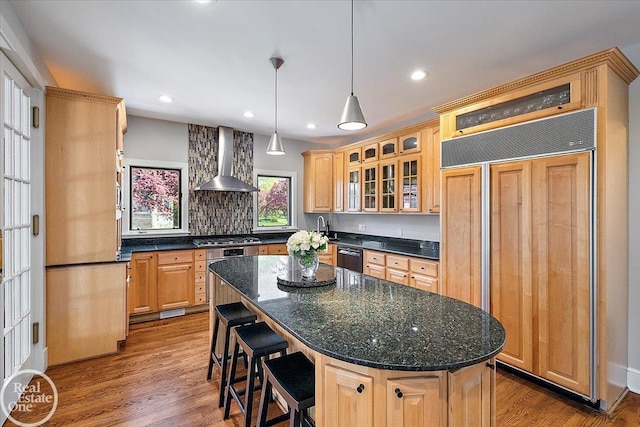 kitchen with wall chimney range hood, a center island, black dishwasher, paneled refrigerator, and stainless steel gas stovetop