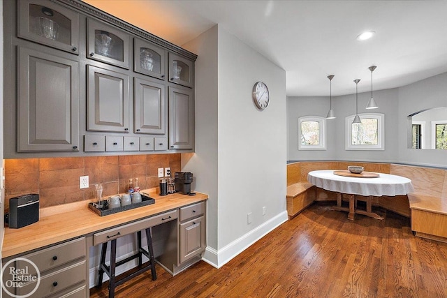 kitchen featuring glass insert cabinets, light countertops, decorative backsplash, and dark wood-type flooring
