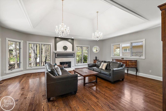 living area with baseboards, a wealth of natural light, dark wood-style floors, and a chandelier
