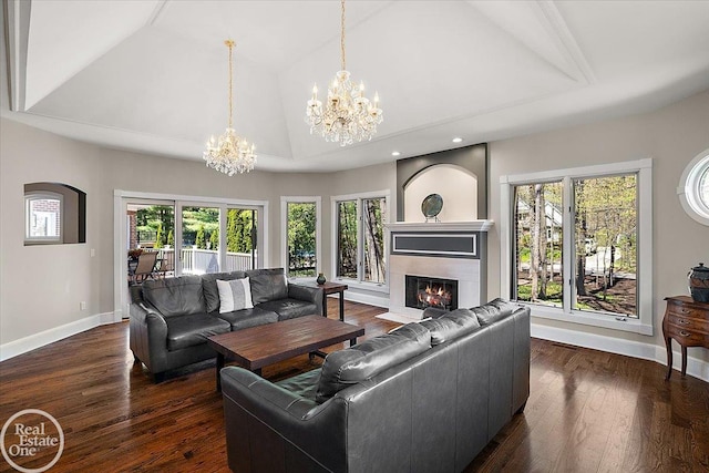 living room featuring a fireplace with flush hearth, baseboards, lofted ceiling, an inviting chandelier, and hardwood / wood-style floors