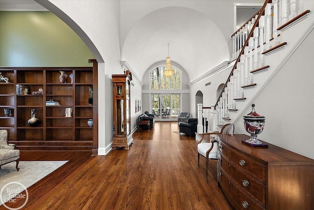 entryway featuring arched walkways, a high ceiling, and dark wood-style flooring