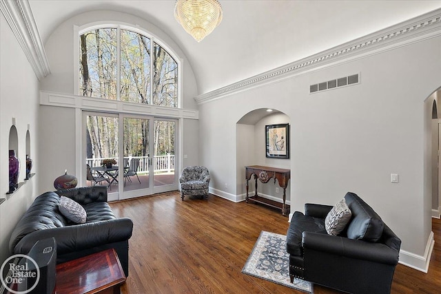 living area with arched walkways, high vaulted ceiling, wood finished floors, and visible vents