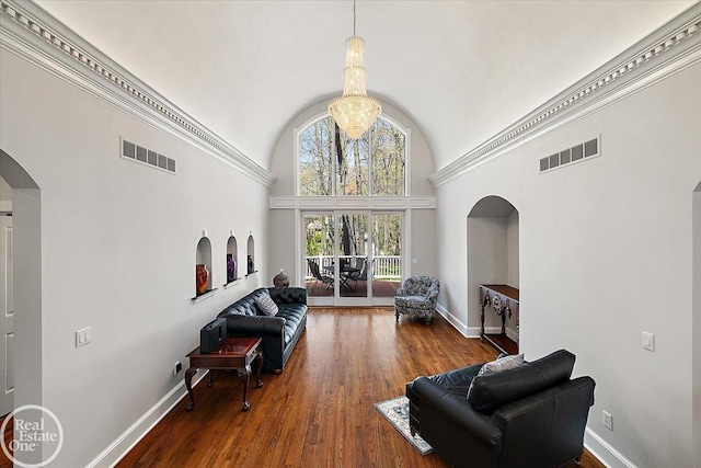 living area with arched walkways, high vaulted ceiling, visible vents, and baseboards