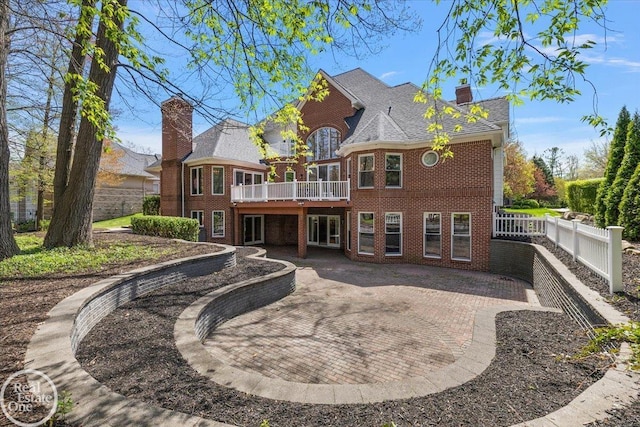 rear view of property with a chimney, a deck, fence private yard, a patio area, and brick siding