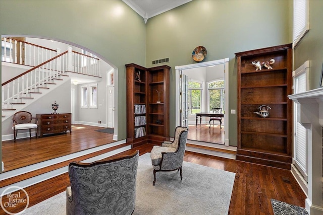 interior space featuring visible vents, a towering ceiling, wood finished floors, stairway, and arched walkways