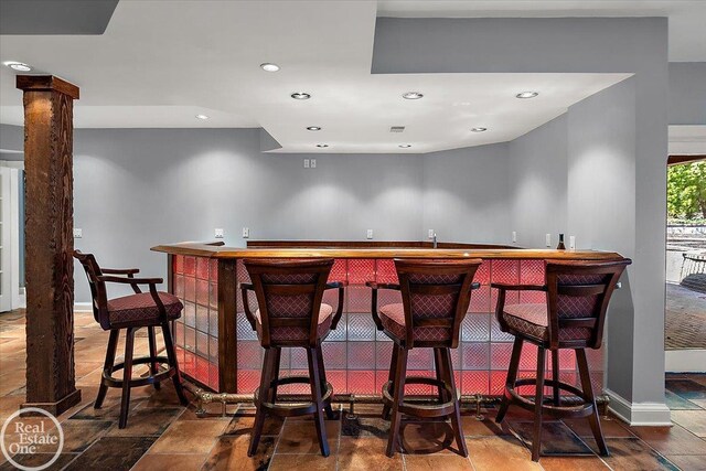 bar with bar, visible vents, a sink, baseboards, and recessed lighting