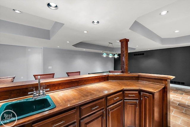 bar featuring indoor wet bar, recessed lighting, a tray ceiling, and a sink