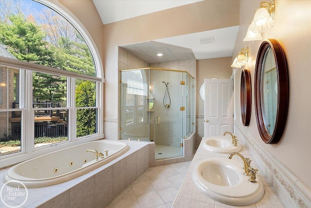 full bath with a tub with jets, a sink, tile patterned flooring, and a stall shower