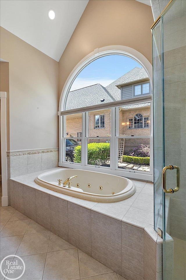 bathroom with tile patterned flooring, a tub with jets, lofted ceiling, and a stall shower