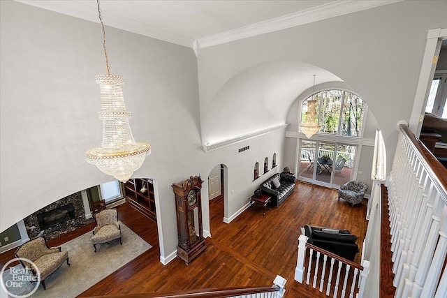 interior space featuring a towering ceiling, wood finished floors, a chandelier, and a fireplace