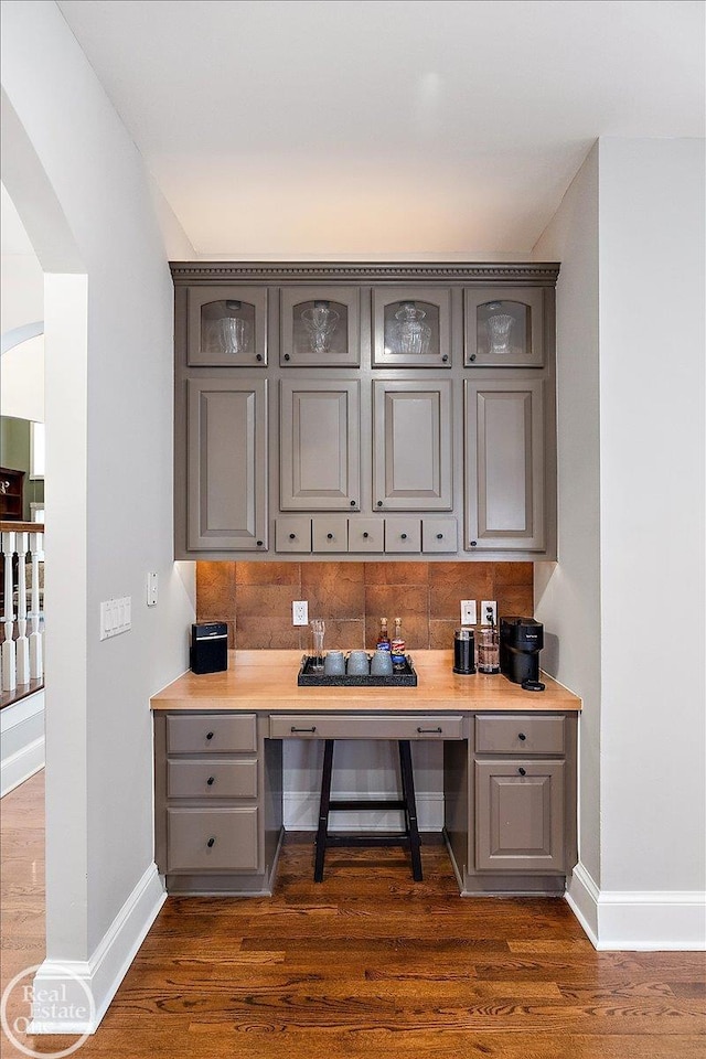 home office with baseboards, dark wood finished floors, and built in study area