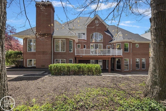 rear view of property featuring roof with shingles, a chimney, and brick siding