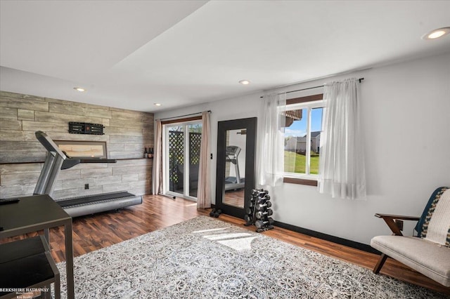 workout area featuring recessed lighting, baseboards, wood walls, and wood finished floors