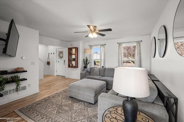 living room featuring baseboards, ceiling fan, visible vents, and wood finished floors