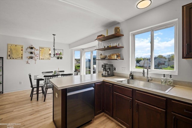 kitchen with stainless steel dishwasher, a sink, a wealth of natural light, and light countertops