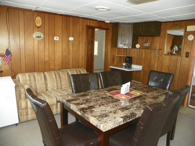 dining room featuring carpet floors and wood walls
