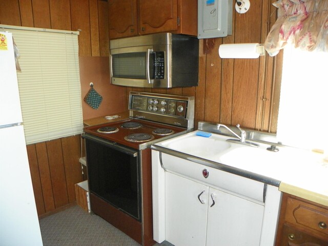 kitchen featuring electric panel, electric range, light countertops, stainless steel microwave, and freestanding refrigerator