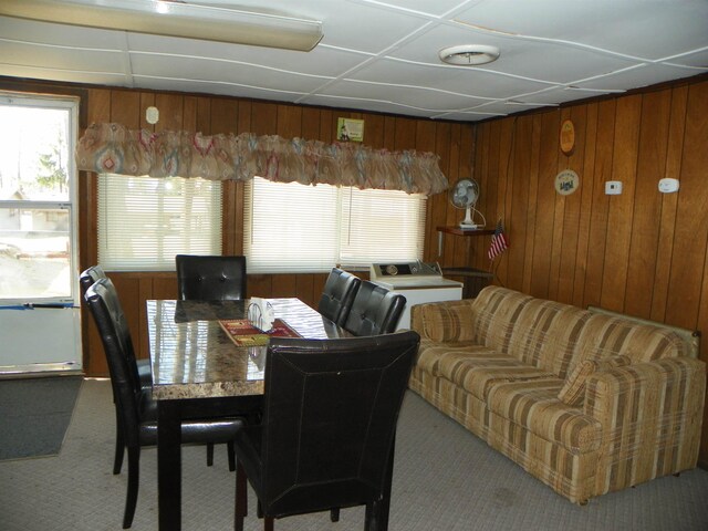 dining room featuring wooden walls and carpet floors