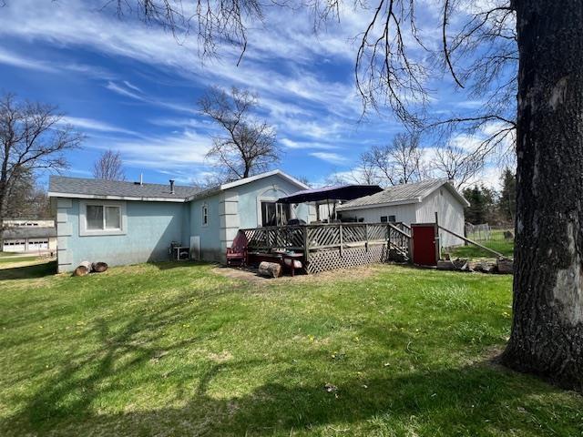 back of property featuring a wooden deck and a yard