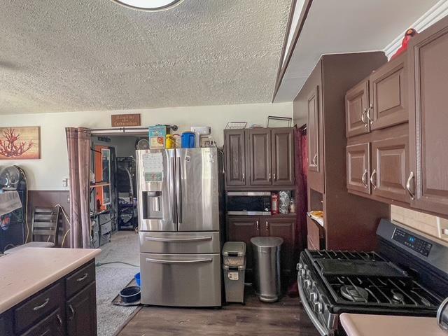 kitchen featuring light countertops, appliances with stainless steel finishes, dark wood finished floors, and a textured ceiling
