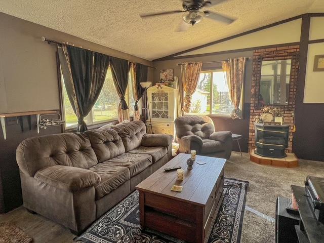 carpeted living room featuring a ceiling fan, a textured ceiling, and vaulted ceiling