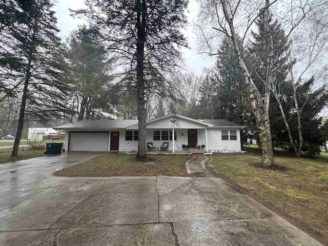 view of front of house with covered porch, concrete driveway, a front lawn, and a garage