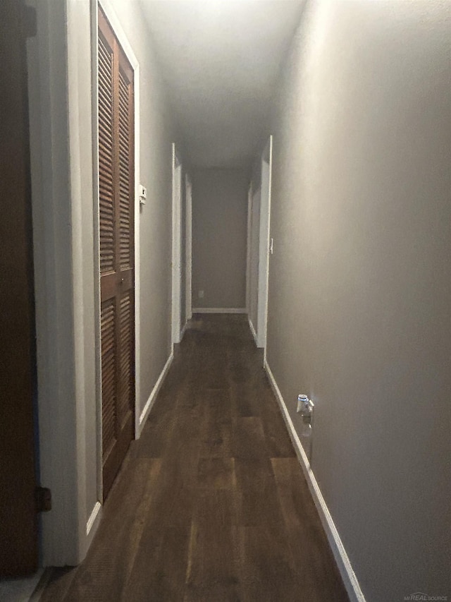 corridor with baseboards and wood finished floors