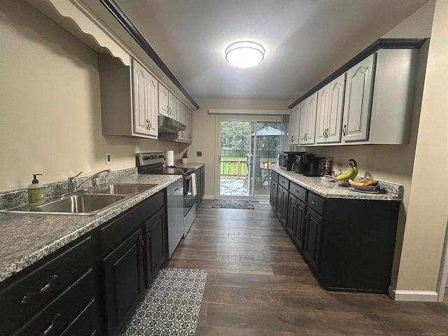 kitchen with appliances with stainless steel finishes, a sink, baseboards, dark wood-style floors, and under cabinet range hood