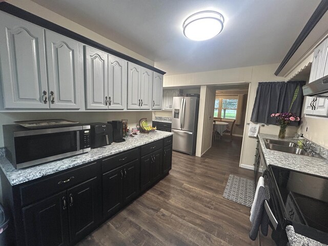kitchen with white cabinets, a sink, dark cabinets, stainless steel appliances, and dark wood-style floors