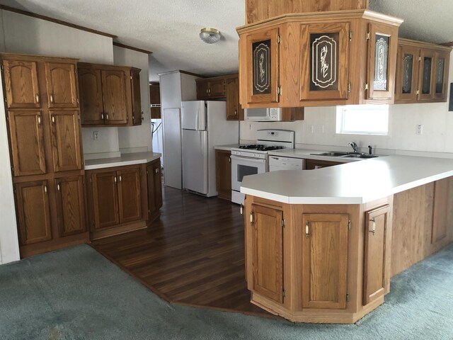 kitchen with a textured ceiling, a sink, light countertops, a peninsula, and white appliances