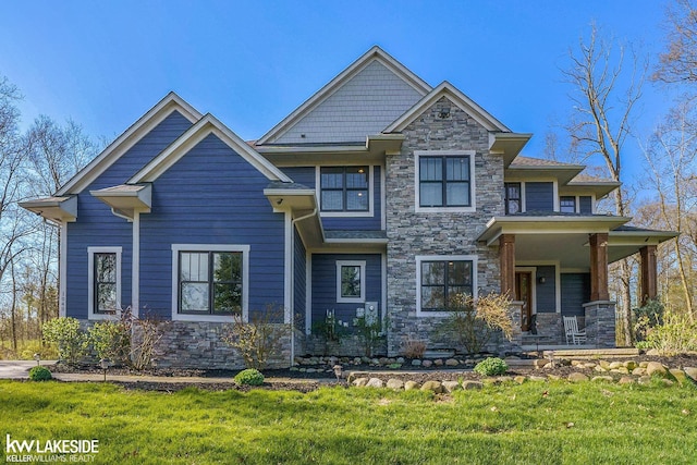 craftsman-style home with a front lawn, covered porch, and stone siding